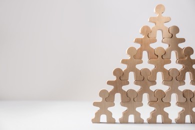 Recruitment process, job competition concept. Pyramid of wooden human figures with noticeable one on top as prime applicant on white table, space for text