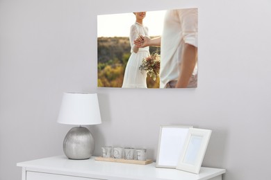 Canvas with printed photo of happy newlywed couple on white wall in room