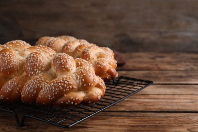 Photo of Closeup view of homemade braided breads with sesame seeds on wooden table, space for text. Traditional Shabbat challah