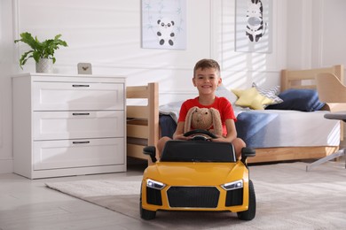 Cute little boy driving big toy car at home, space for text
