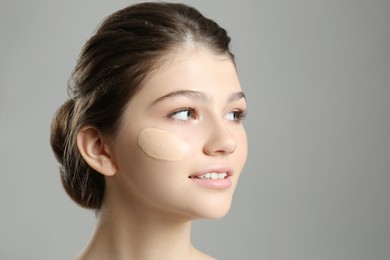 Beautiful girl with foundation smear on her face against grey background