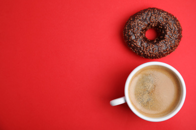 Delicious coffee and donut on red background, top view with space for text. Sweet pastries