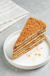 Slice of delicious layered honey cake on grey table