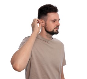 Young man cleaning ear with cotton swab on white background