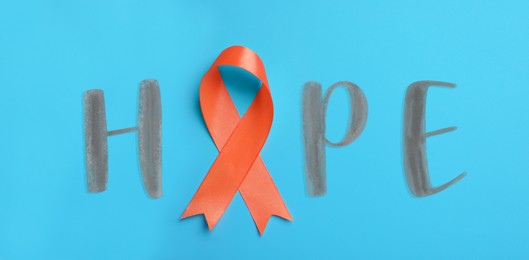 Orange awareness ribbon and word HOPE on light blue background, top view. Banner design