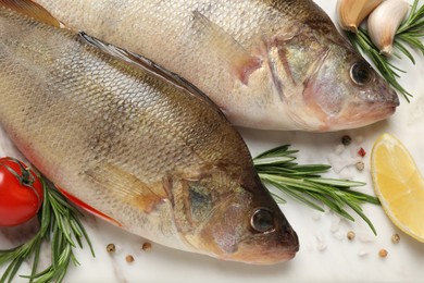 Fresh raw perches and ingredients on white marble table, closeup. River fish