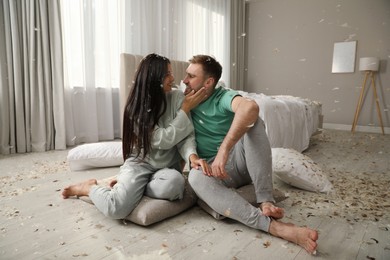 Happy young couple resting after fun pillow fight in bedroom