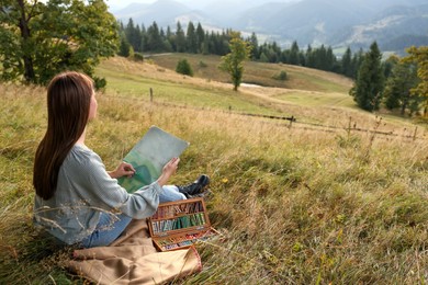 Young woman drawing landscape with soft pastels in nature. Space for text