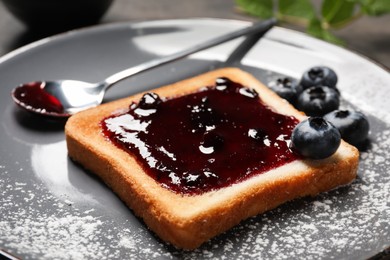 Delicious toast with jam and blueberries on plate, closeup