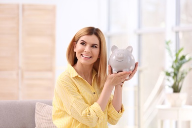 Portrait of woman with piggy bank at home