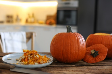 Fresh ripe pumpkins on wooden table in kitchen, space for text. Halloween celebration