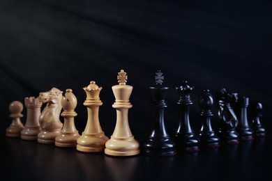 Photo of White and black chess pieces against dark background. Competition concept
