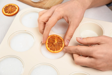 Woman making natural handmade soap at white table, closeup