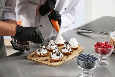 Pastry chefs preparing desserts at table in kitchen, closeup