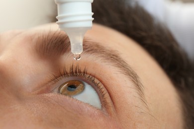 Closeup view of man using eye drops