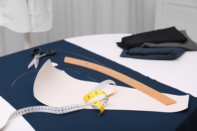 Ruler, measuring tape, paper template and fabric on table in tailor workshop