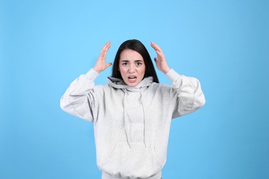 Portrait of stressed young woman on light blue background