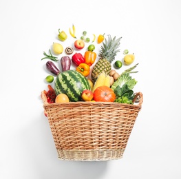 Photo of Basket with assortment of fresh organic fruits and vegetables on white background, top view