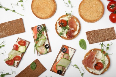 Tasty rusks and rye crispbreads with different toppings on white background, top view