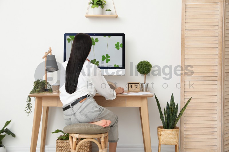 Photo of Young woman working at table in light room, back view. Home office