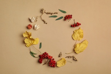 Dried flowers, leaves and berries arranged in shape of wreath on beige background, flat lay with space for text. Autumnal aesthetic