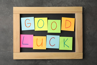 Notes with phrase GOOD LUCK on grey stone background, top view