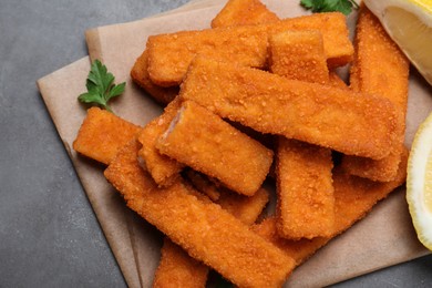 Fresh breaded fish fingers served on grey table, top view