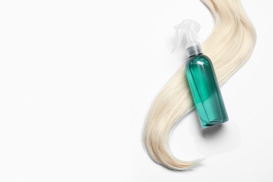 Photo of Spray bottle with thermal protection and lock of blonde hair on white background, flat lay. Space for text