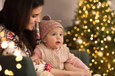 Happy young mother with her cute baby in room decorated for Christmas. Winter holiday