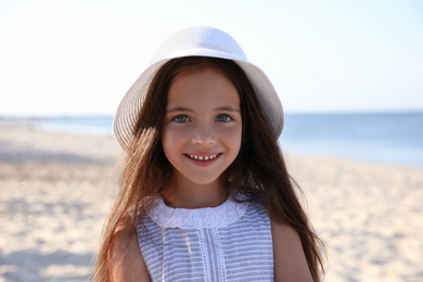 Cute little child wearing hat at sandy beach on sunny day