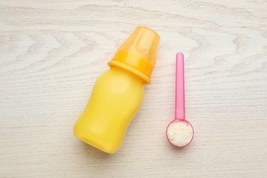 Feeding bottle with infant formula and powder on white wooden table, flat lay