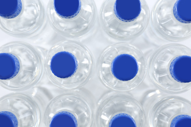 Plastic bottles with pure water as background, top view