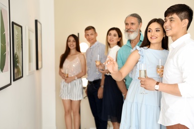 Group of people with glasses of champagne at exhibition in art gallery
