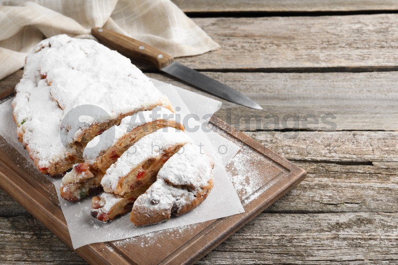 Traditional Christmas Stollen with icing sugar on wooden table, space for text