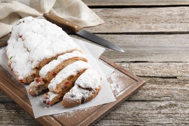 Traditional Christmas Stollen with icing sugar on wooden table, space for text