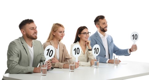 Panel of judges holding signs with highest score at table on white background