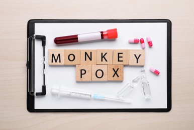 Photo of Flat lay composition with words Monkeypox made of squares and test tube on wooden table