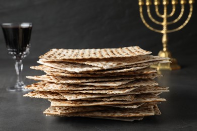 Stack of traditional matzos near red wine on grey table