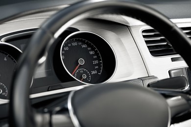 Speedometer on car dashboard, view through steering wheel