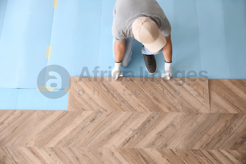 Worker installing laminated wooden floor indoors, above view