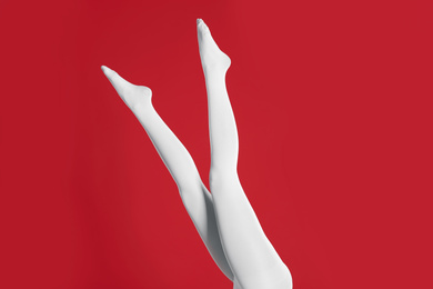 Woman wearing white tights on red background, closeup of legs