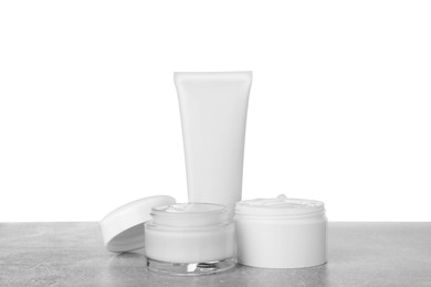 Jars and tube of hand cream on gray table against white background