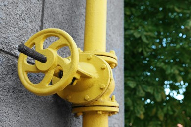 Photo of Yellow gas pipe on grey wall outdoors, closeup. Space for text