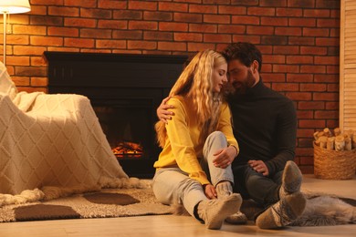 Photo of Lovely couple spending time together near fireplace in room