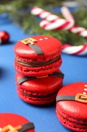 Photo of Beautifully decorated Christmas macarons on blue background, closeup