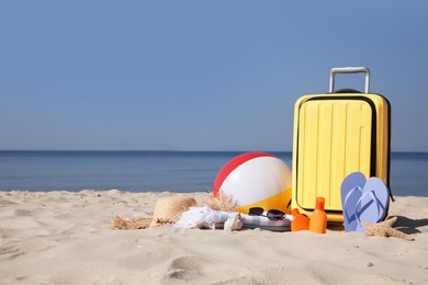 Suitcase and beach accessories on seaside. Space for text
