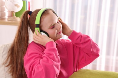 Cute indie girl in headphones listening music at home