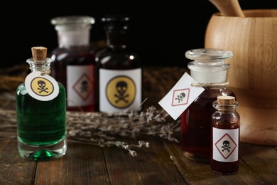 Bottles with different poisons on wooden table