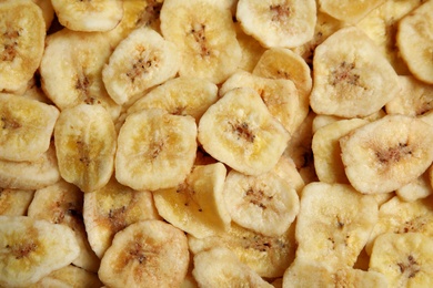 Sweet banana slices as background, top view. Dried fruit as healthy snack