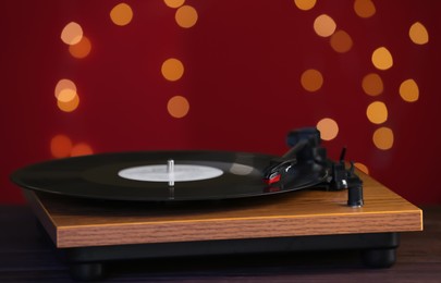 Turntable with vinyl record against blurred lights. Space for text
